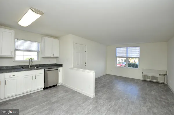 a large white kitchen with granite countertop a stove a sink and white cabinets