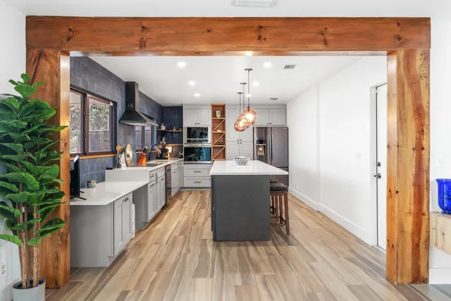 a kitchen with stainless steel appliances granite countertop a lot of cabinets and wooden floor