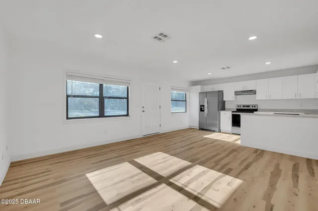 a view of kitchen and empty room with wooden floor