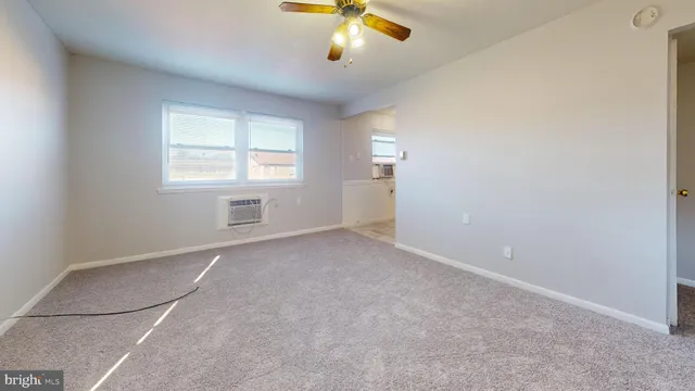 an empty room with windows and fan