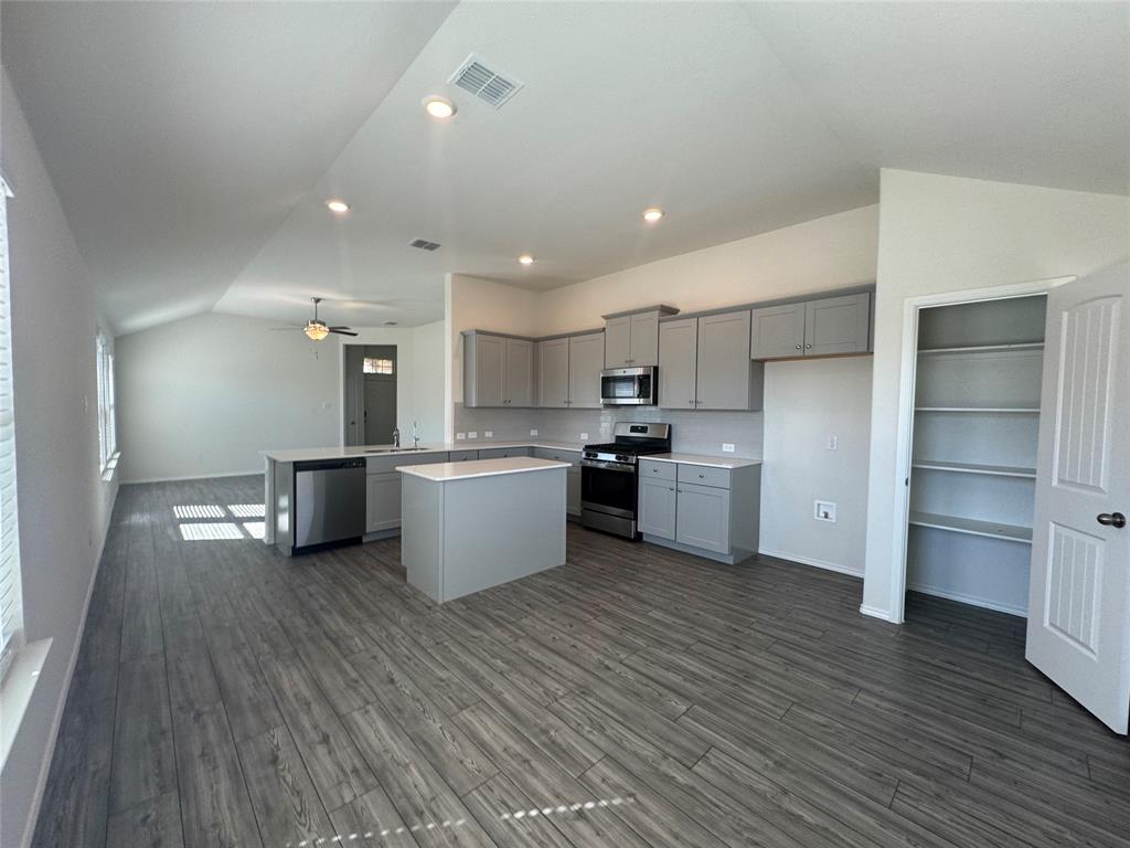 4700 Essonite Road Little Elm, TX 76227 - Photo 14 of 37 a kitchen with stainless steel appliances kitchen island wooden cabinets and refrigerator