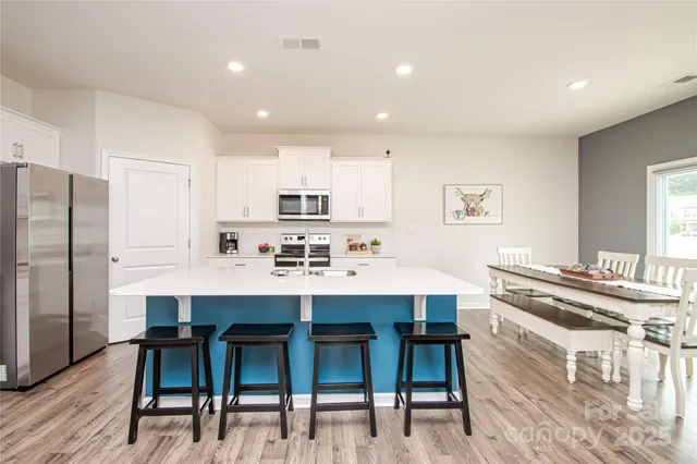 a kitchen with stainless steel appliances a table chairs refrigerator and wooden cabinets