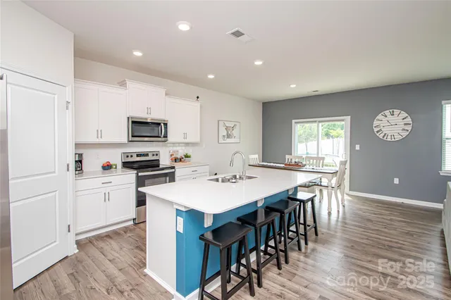 a kitchen with appliances a sink a stove a table and chairs