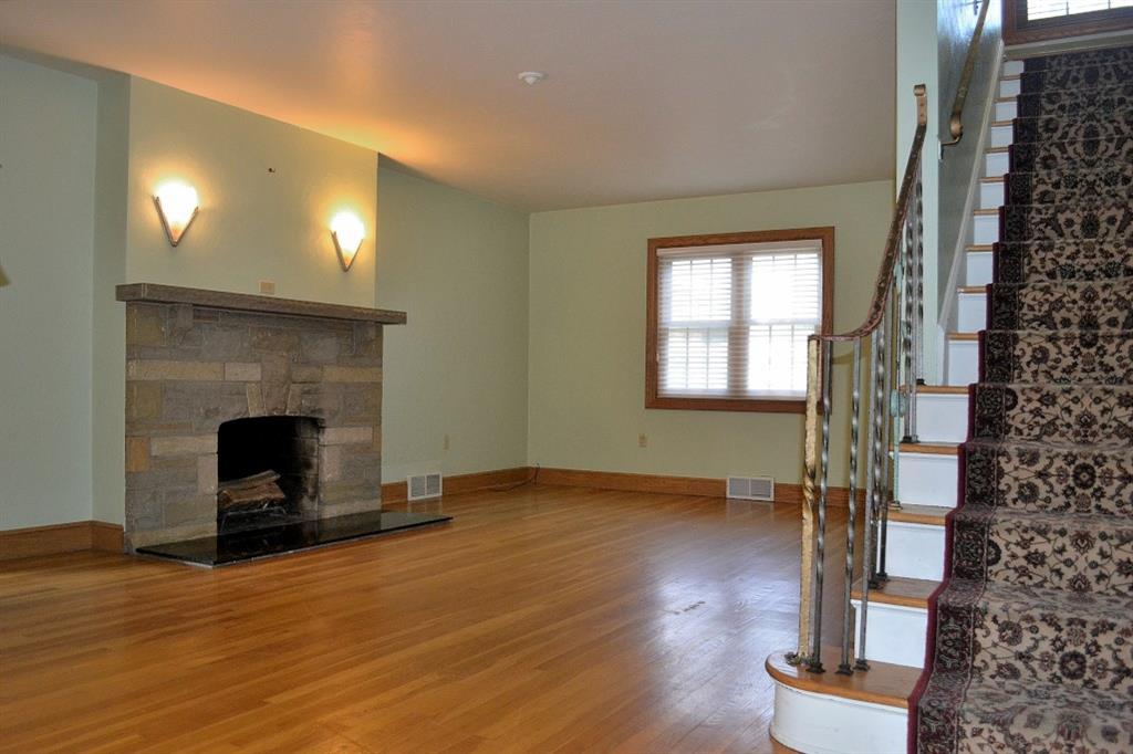 138 Siebert Road Pittsburgh, PA 15237 - Photo 3 of 25 Living Room: The covered porch leads to the front entry with a newer front door. The immediate view is that of the spacious living room. Here, there are beautiful hardwood floors, a log-burning fireplace with a stone surround and a marble hearth, attractive sconces above the mantle and silhouette shades covering the newer multi-paned windows. The original iron handrail on the hardwood staircase has lovely detail.