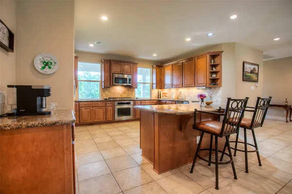 a kitchen with stainless steel appliances granite countertop a stove a sink a microwave a dining table and chairs