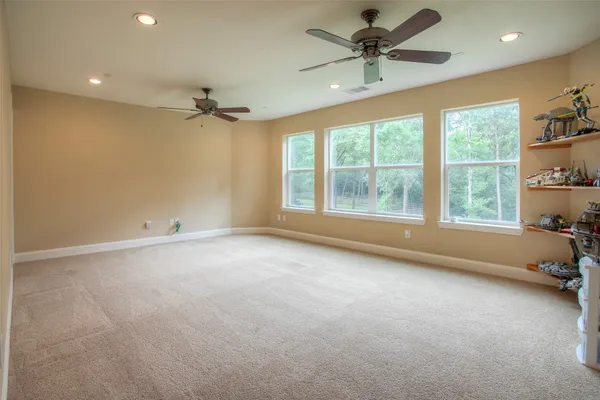 an empty room with chandelier fan and windows