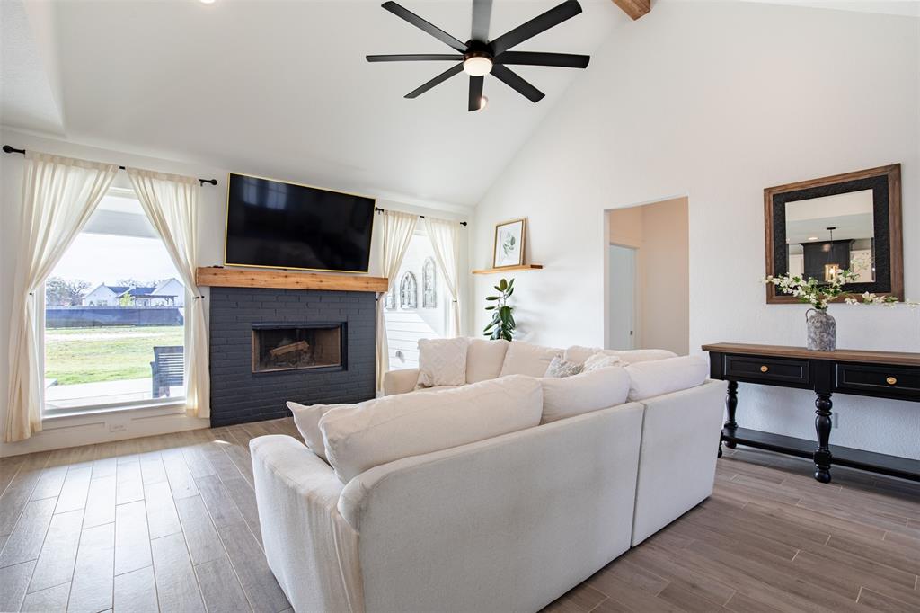 111 Bluegrass Trail Springtown, TX 76082 - Photo 11 of 37 Living room anchored by a wood burning fireplace and windows overlooking the covered back patio and spacious yard.