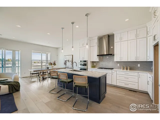 a open kitchen with stainless steel appliances kitchen island granite countertop a stove a sink a dining table and chairs with wooden floor