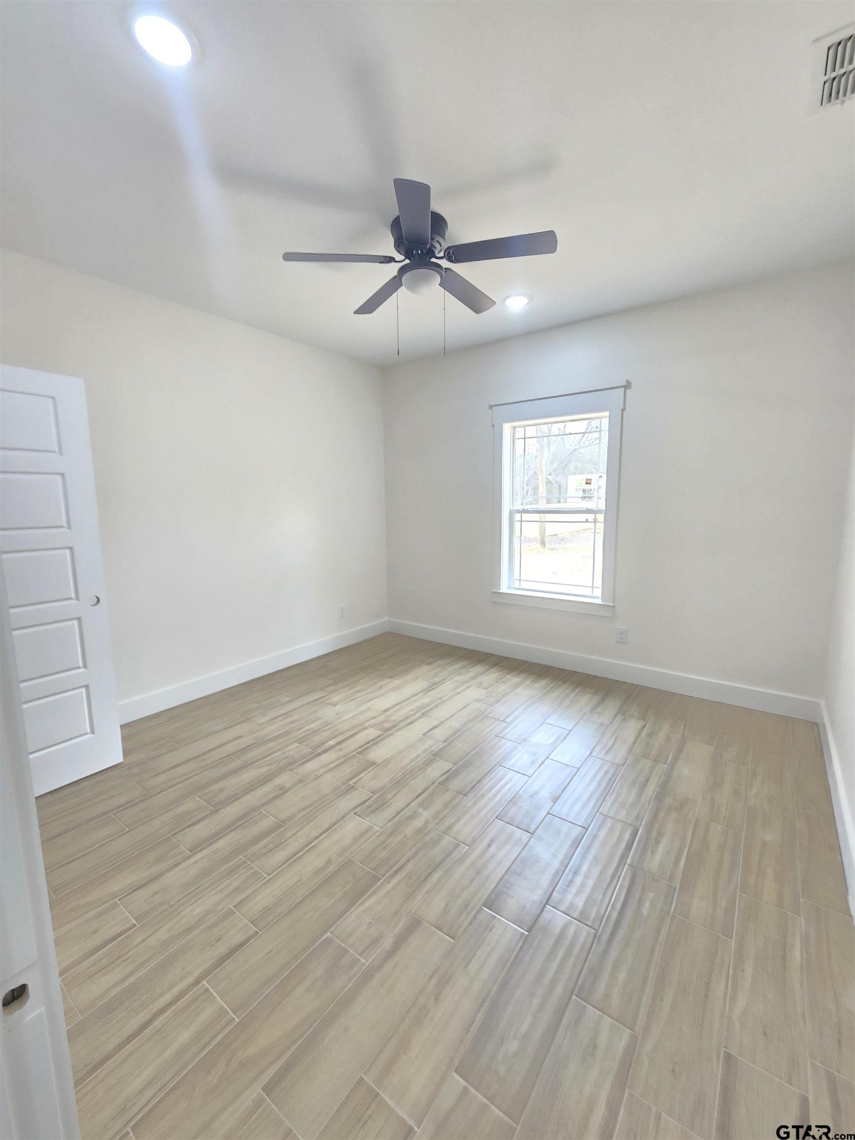 7227 Cr 485 Tyler Tx 75706 Tyler, TX 75706 - Photo 11 of 23 an empty room with wooden floor ceiling fan and windows