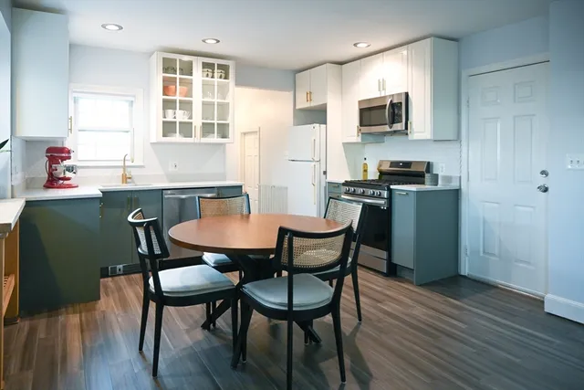 a kitchen with stainless steel appliances a dining table chairs microwave and sink
