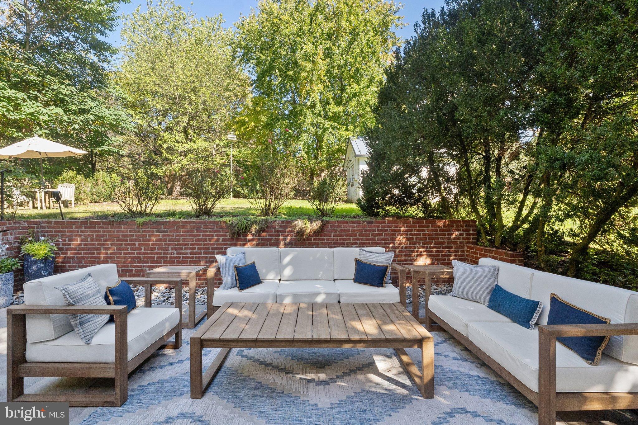 677 Federal Street Paris, VA 20130 - Photo 52 of 82 a view of a patio with couches and a table and chairs under an umbrella with large trees