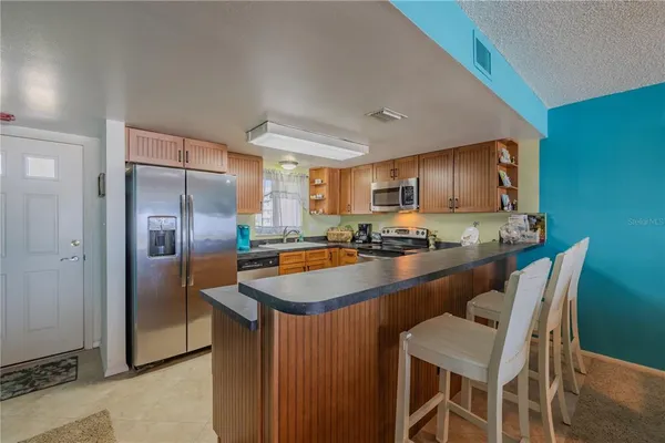 a kitchen with granite countertop stainless steel appliances a refrigerator a stove top oven and sink