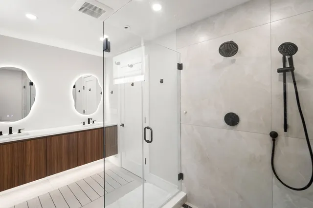 a bathroom with a double vanity sink mirror and shower