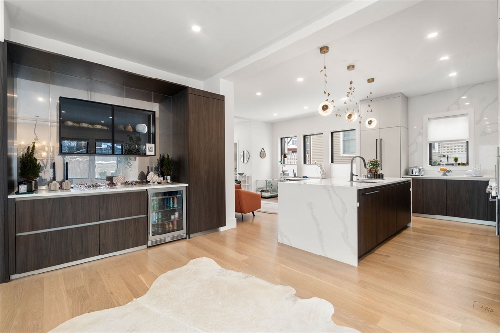 116 Thorndike Street, Unit 1 Brookline, MA 02446 - Photo 6 of 16 a large white kitchen with kitchen island a sink a center island stainless steel appliances and a cabinets
