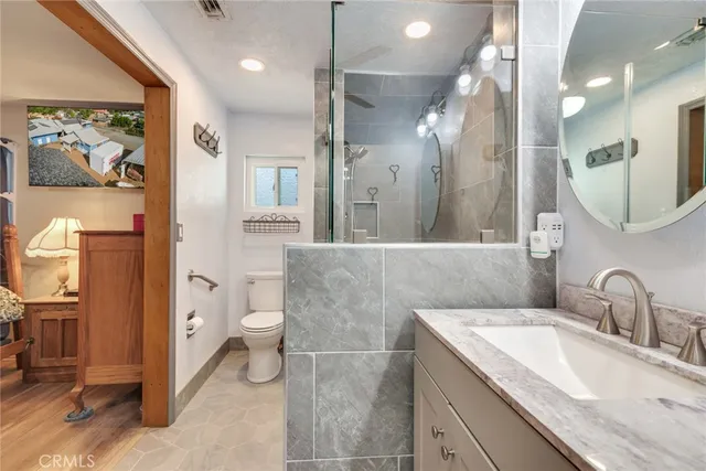 a bathroom with a granite countertop sink a toilet and a mirror