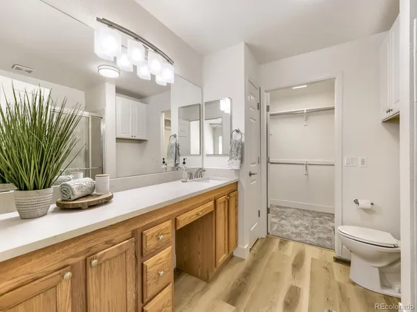 a spacious bathroom with a granite countertop sink a toilet a mirror and shower
