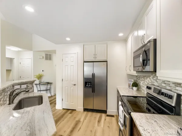 a kitchen with granite countertop a sink stove and refrigerator
