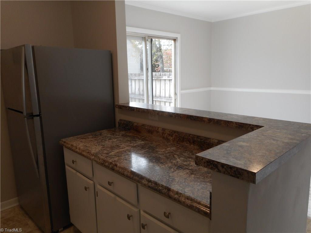 5725 Bramblegate Road, Unit F Greensboro, NC 27409 - Photo 13 of 30 Kitchen: Room features include fresh new paint, new vinyl flooring for easy cleaning, crown molding, bright cabinets with new counter tops, sink and fixtures. You also have a brand new SST dishwasher, slide in stove and refrigerator that stays with the home at closing. To the right side is the dining room, laundry room and sliding door to the patio.