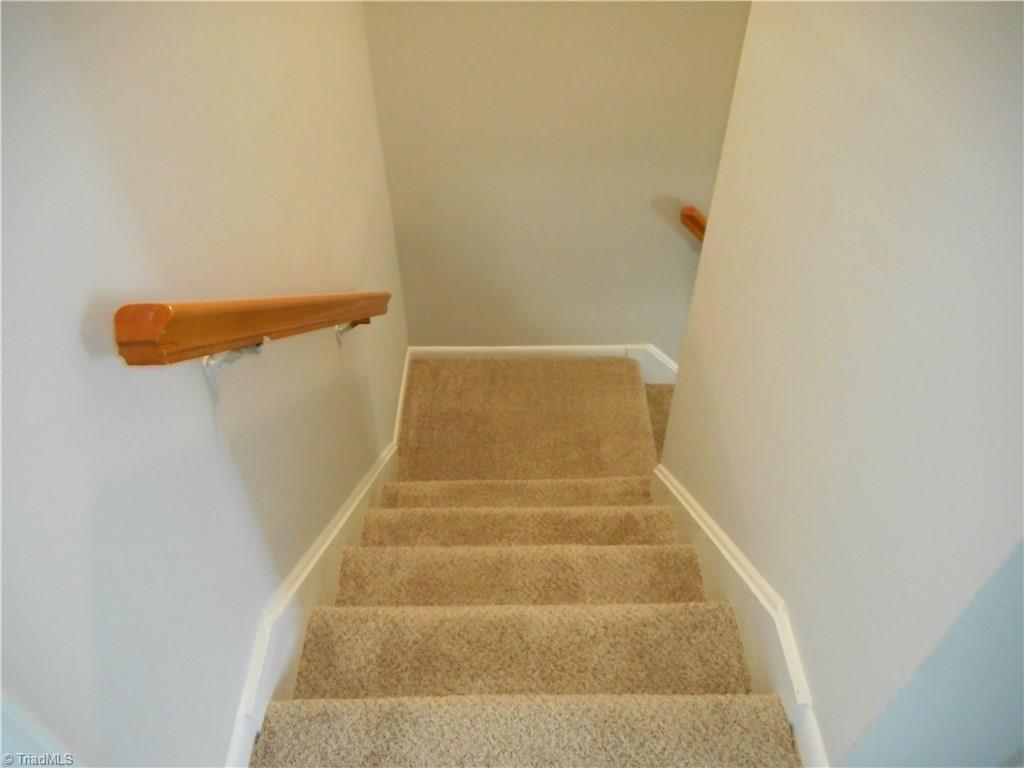5725 Bramblegate Road, Unit F Greensboro, NC 27409 - Photo 28 of 30 Stairway Looking Down to Main Level: here we can see that the stairs are covered with new carpeting and fresh new paint.