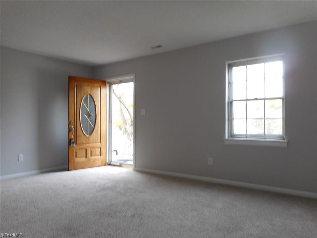 5725 Bramblegate Road, Unit F Greensboro, NC 27409 - Photo 5 of 30 Living Room: Room features include fresh new paint, new carpet flooring and a window for natural lighting. The front door on the right is from the front parking lot area. To the left is the staircase, kitchen, laundry, dining room and half bath.