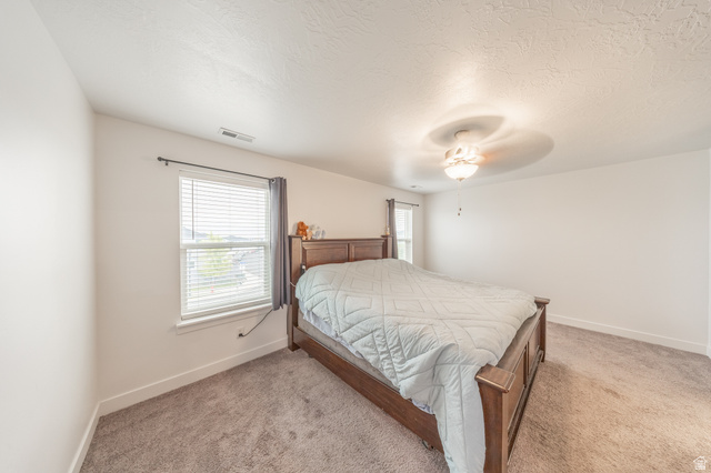 4765 Breezy Patch Road Eagle Mountain, UT 84005 - Photo 16 of 25 Bedroom featuring neutral wall paint, textured ceiling, brown carpet, and a window with blinds