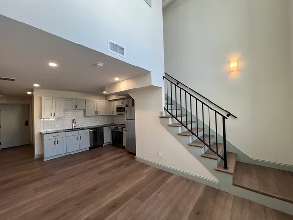 a large kitchen with a center island wooden floor and stainless steel appliances
