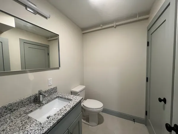 a bathroom with a granite countertop sink toilet and mirror
