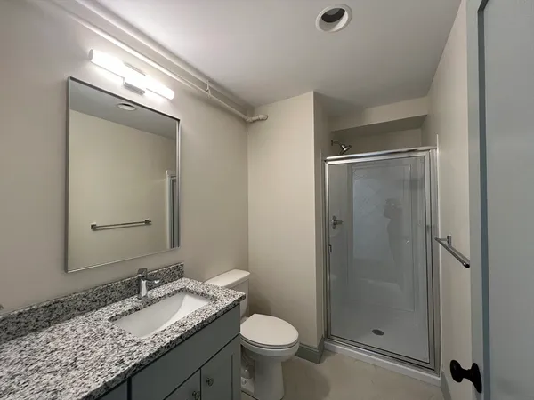 a bathroom with a granite countertop sink toilet and shower