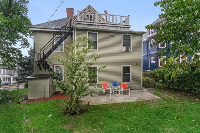 a view of a house with table and chairs in a yard