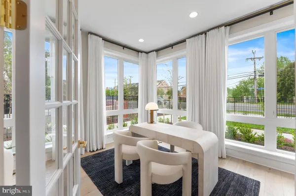 a dinning area with furniture large windows and wooden floor