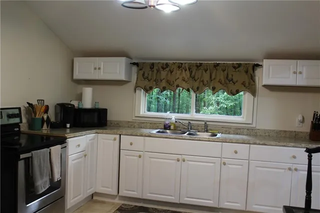 a kitchen with white cabinets and window