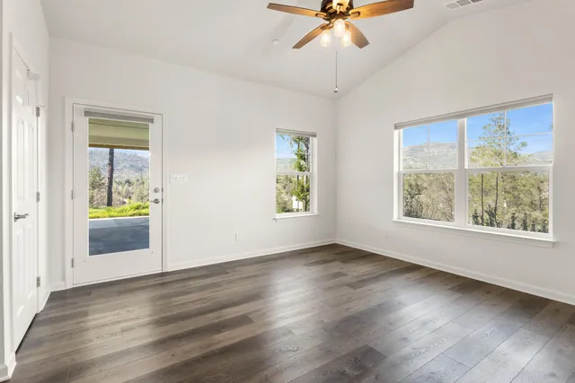 a view of an empty room with a window and wooden floor