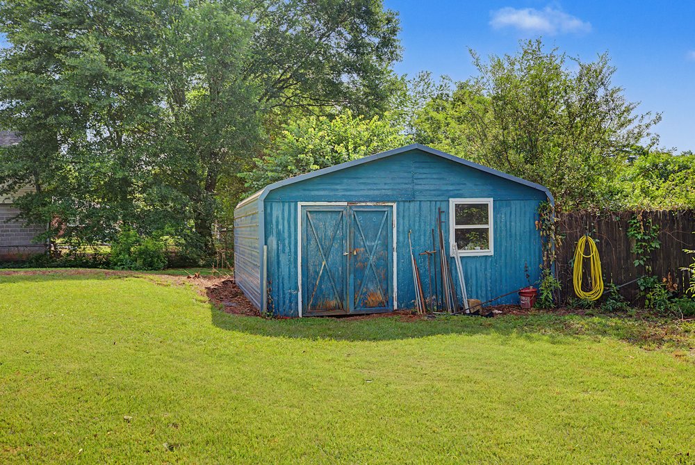 115 Brunson Drive Pickens, SC 29671 - Photo 26 of 29 A vibrant blue storage shed offers practical utility amidst a verdant, well-maintained yard.