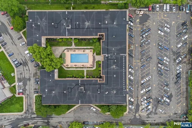 an aerial view of a tennis ground and a cars park side of the road