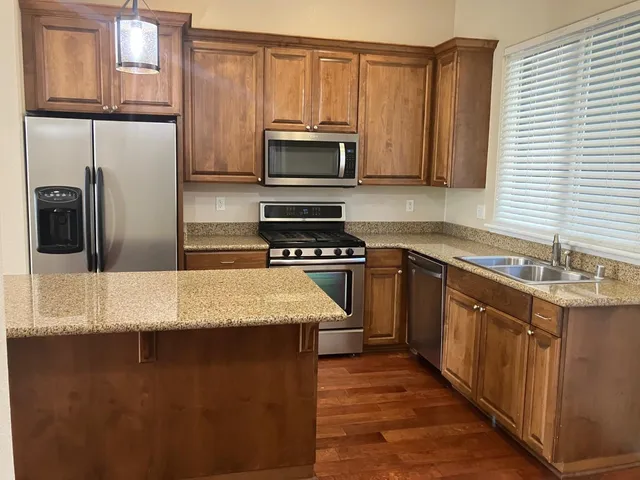 a kitchen with stainless steel appliances granite countertop a sink a stove and a refrigerator