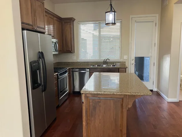 a view of a livingroom with furniture wooden floor chandelier and a kitchen
