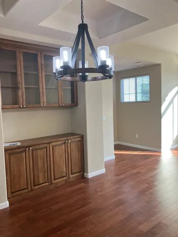 a view of a room with wooden floor chandeliers and kitchen appliances