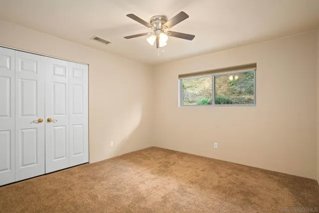 an empty room with windows and fan