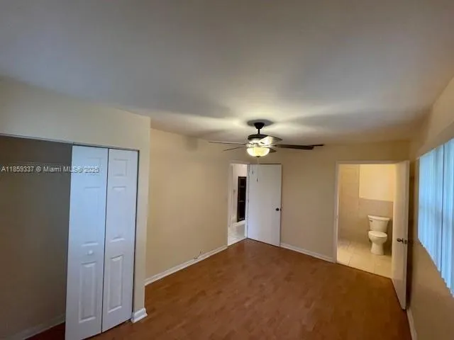 a view of a room that has a large window and chandelier fan