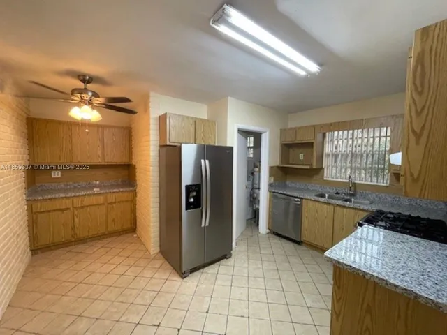 a large kitchen with a refrigerator a stove a sink dishwasher with a dining table and chairs