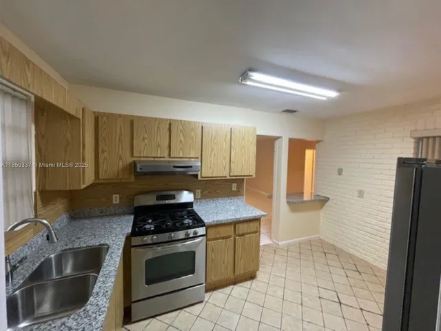 a kitchen with granite countertop a stove a refrigerator and a sink