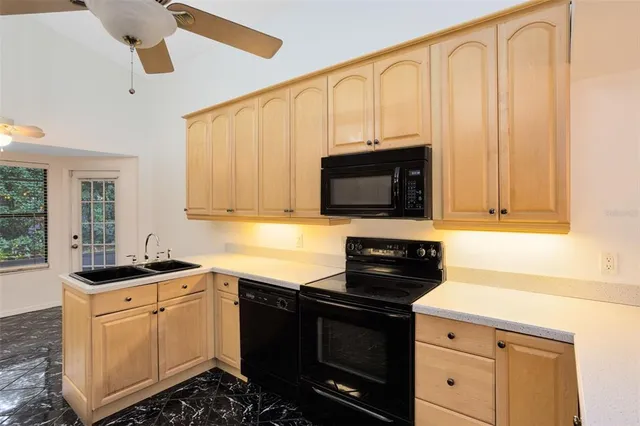 a kitchen with granite countertop a sink dishwasher a stove and a microwave oven with cabinets