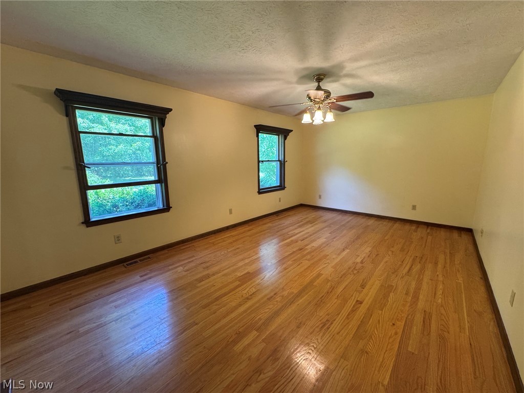 8201 Orchard Road Painesville, OH 44077 - Photo 21 of 45 Spacious living room featuring wood-finish flooring, two large windows with dark wood trim, a ceiling fan with integrated lighting, and light-toned walls
