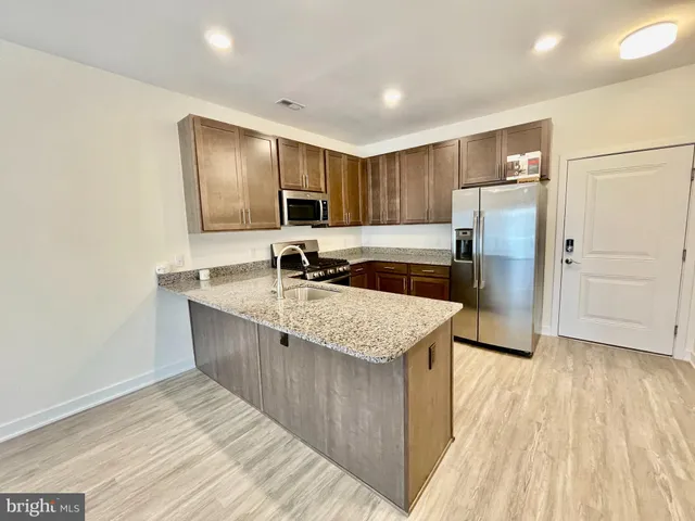 a kitchen with kitchen island granite countertop a sink and refrigerator
