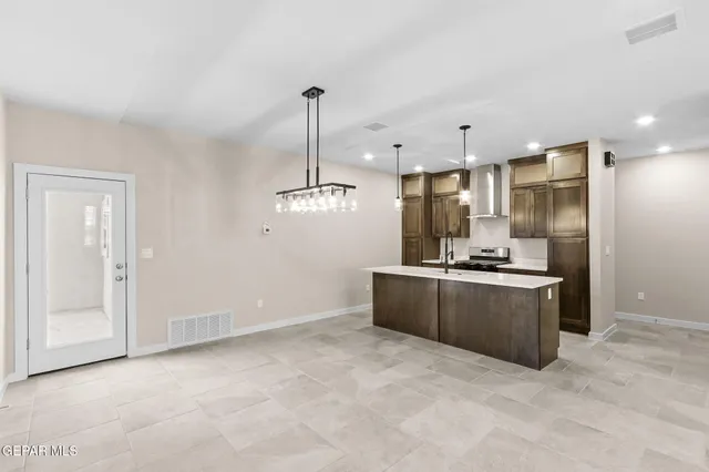 a large kitchen with stainless steel appliances kitchen island granite countertop a refrigerator a sink and a stove