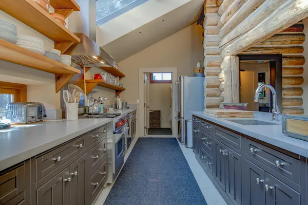 a room with stainless steel appliances lots of wooden furniture dining table and chairs