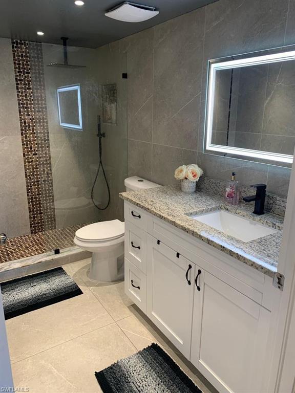 a bathroom with a granite countertop toilet sink and mirror