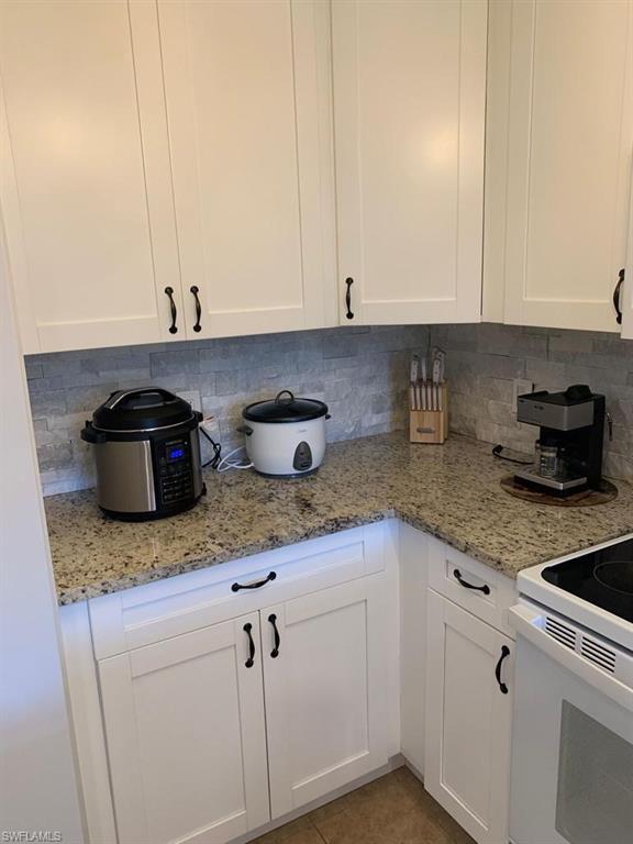 8224 Key Royal Circle, Unit 223 Naples, FL 34119 - Photo 16 of 17 a kitchen with granite countertop white cabinets and a sink
