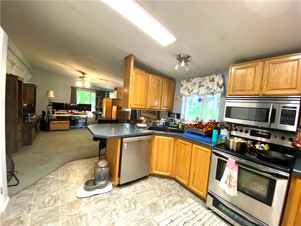 18436 Loganberry Street Southwest Rochester, WA 98579 - Photo 7 of 29 a kitchen with stainless steel appliances granite countertop a stove a sink and a microwave