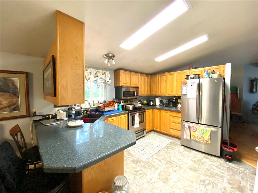 18436 Loganberry Street Southwest Rochester, WA 98579 - Photo 8 of 29 a kitchen with stainless steel appliances granite countertop sink refrigerator and microwave